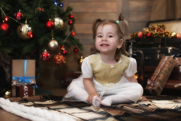 Na véspera do natal, bebezinho sentado no chão brincando com brinquedos