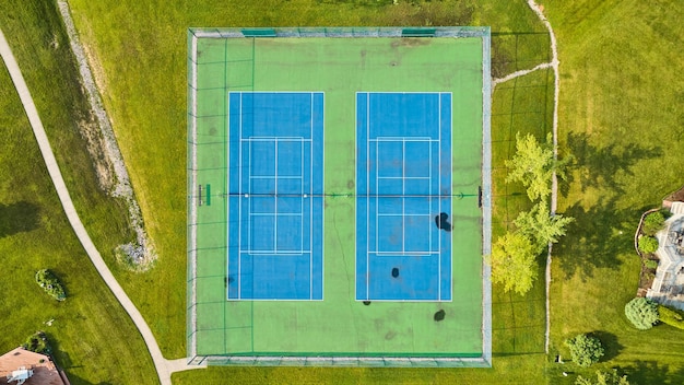 Nachbarschaftstennisplatz mit blauem und grünem Spielfeld mit abgenutzten Flecken auf der Bodenantenne