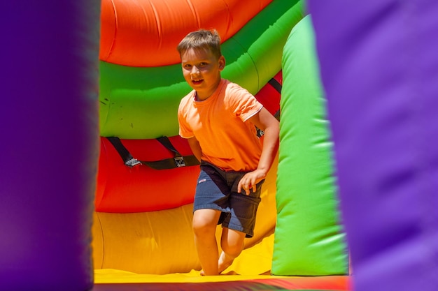 Nachdem das Kind von einer aufblasbaren hellen Rutsche auf ein Trampolin heruntergerollt ist, rennt es los, um zu spielen