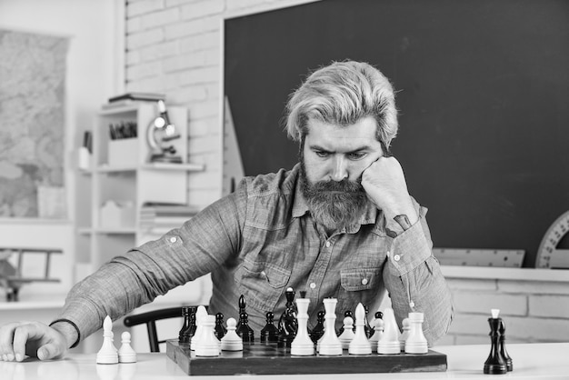 Nachdenken über den nächsten Schritt Schach ist ein Gymnasium des Geistes Schachunterricht Strategiekonzept Schullehrer Brettspiel Figuren auf Holzschachbrett Intelligenter Hipster-Mann, der Schach spielt Intellektuelles Hobby