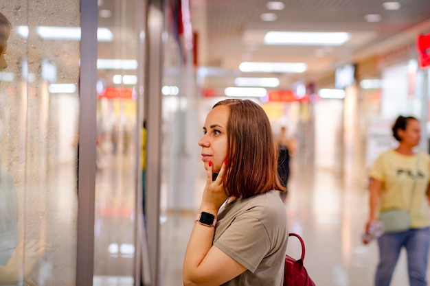 Nachdenkliche Dame, die in der Nähe der Vitrine im modernen Einkaufszentrum steht