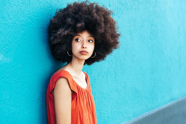 Nachdenkliche Frau mit Afro-Haaren blickt in die Kamera