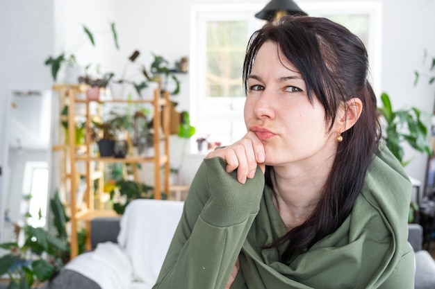 Nachdenkliche Gefühle einer Frau in ihrem Zuhause in einem hellen, modernen Interieur mit heimischen Pflanzen Porträt einer verträumten Person