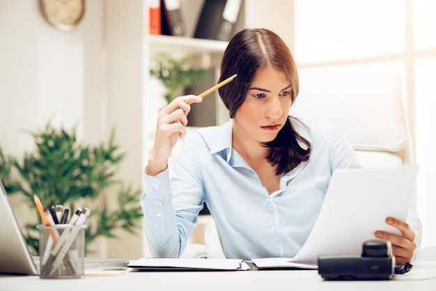 Nachdenkliche junge Frau im Büro Brainstorming über Geschäftsbericht.