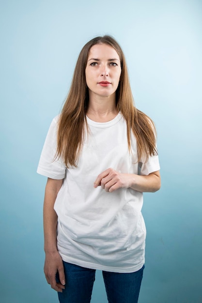 Nachdenkliche junge Frau in weißen T-Shirt-Jeans auf blauem Hintergrund