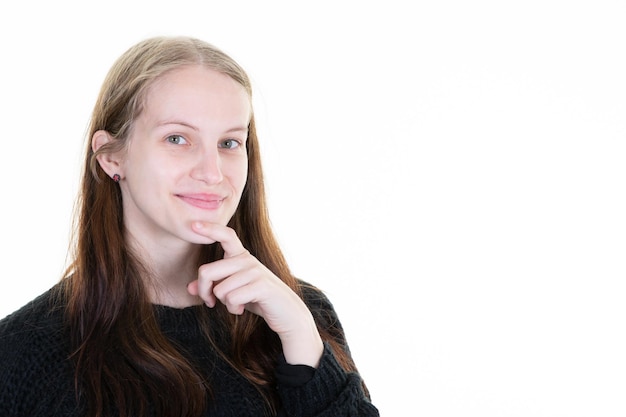 Nachdenkliche schöne junge Frau, die auf der Suche nach glücklichem Gesicht lächelt, niedliches Lächeln, das im weißen Kopierraum-Wandhintergrund posiert