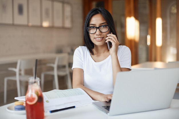 Nachdenkliche und kluge Unternehmerin, die vom Café entfernt arbeitet