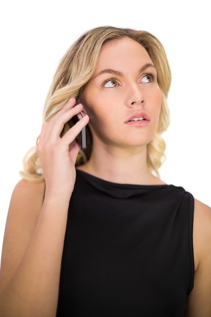 Nachdenkliche wunderschöne Blondine im schwarzen Kleid am Telefon