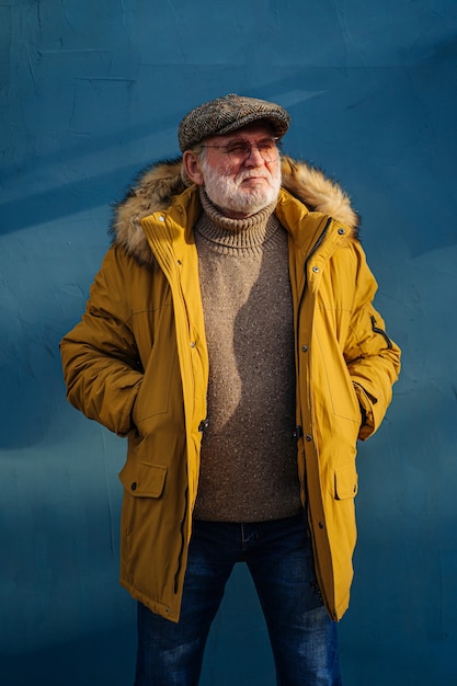 Nachdenklicher alter Mann in stylischer Oberbekleidung, der die Hände in den Taschen hält