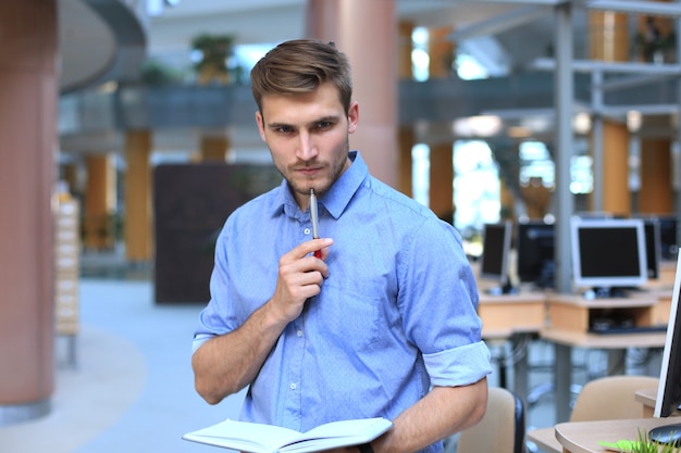 Nachdenklicher junger Mann, der in seinem Büro steht.