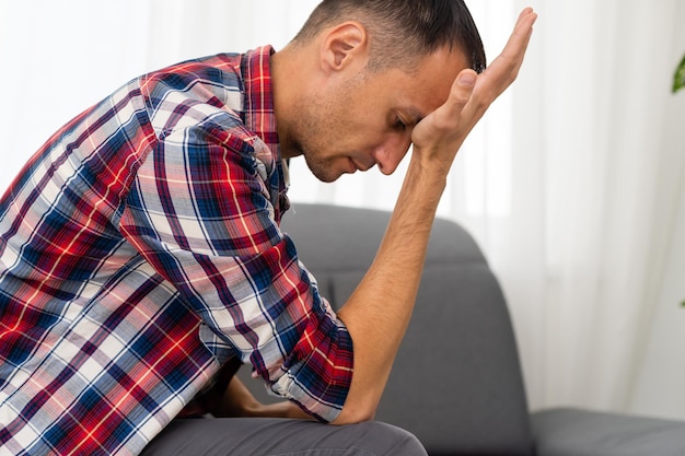 Nachdenklicher junger Mann im Wohnzimmer