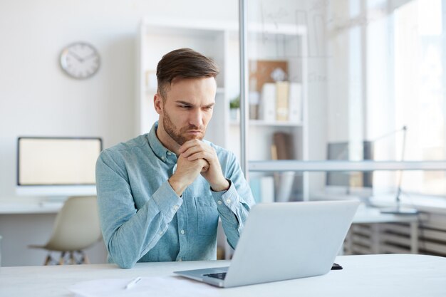 Nachdenklicher junger Mann mit Laptop