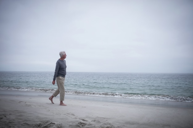 Nachdenklicher Mann im Ruhestand zu Fuß am Strand