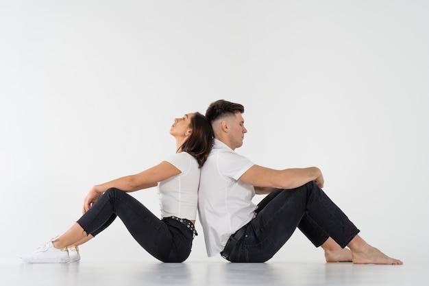 Nachdenklicher Mann und Frau sitzen Rücken an Rücken nach Streit auf Weiß