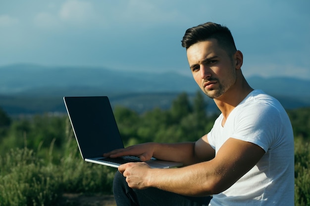 Nachdenklicher muskulöser Mann mit Laptop im Freien