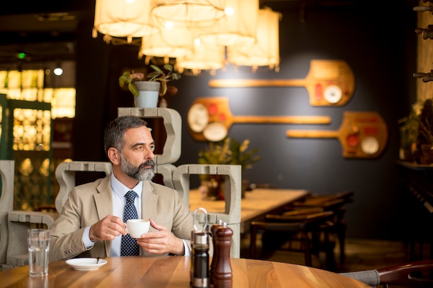 Nachdenklicher reifer Geschäftsmann, der Kaffee im Café trinkt