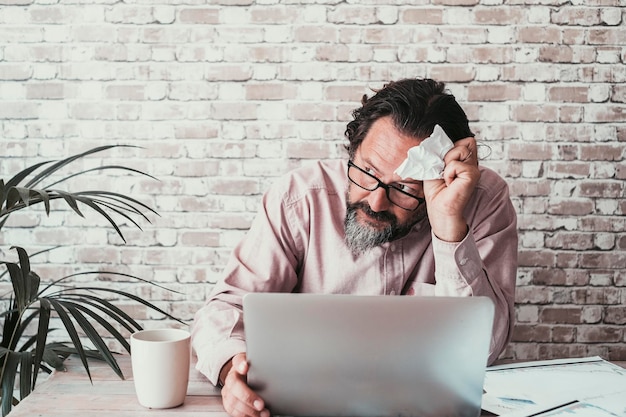 Nachdenklicher reifer Mann vor einem Computer, der online arbeitet Menschen, die intelligentes Arbeiten und Probleme leben Stress und besorgte Arbeiter am Laptop im Heimbüro Konzept der Ausfallzeit der bankrotten Wirtschaft