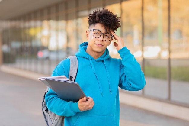 Foto nachdenklicher schüler, der seine brille anpasst und den kopierraum berührt