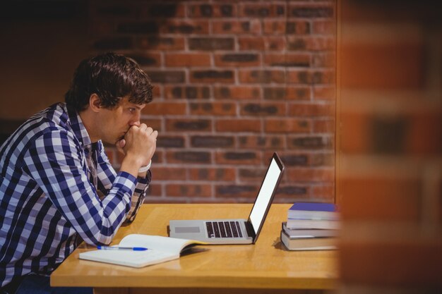 Nachdenklicher Student mit Laptop in der Bibliothek