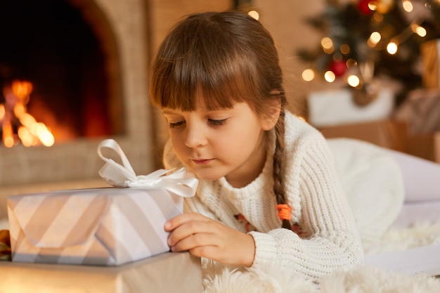 Nachdenkliches kind mit weihnachtsgeschenk zu hause