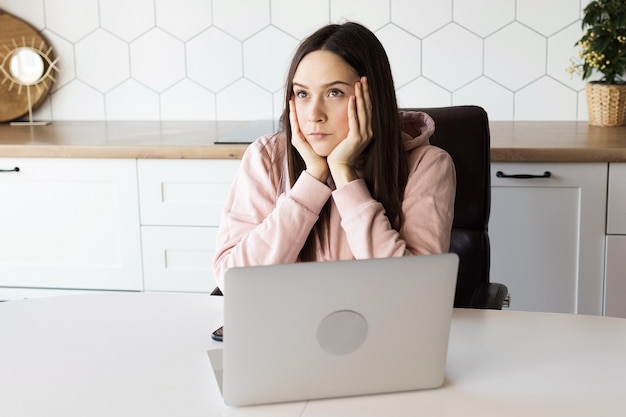 Nachdenkliches Mädchen bei der Arbeit am Computer, arbeiten von zu Hause aus online