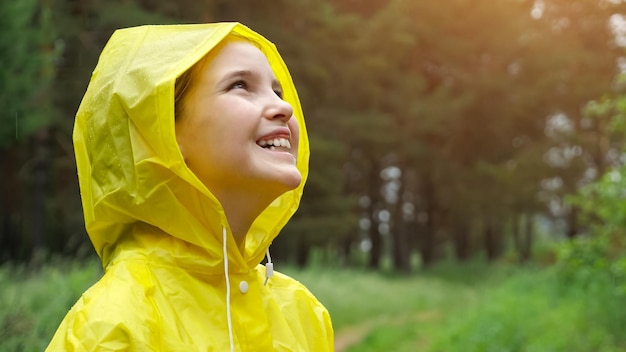 Nachdenkliches Mädchen schaut weg und genießt Regenwetter im Wald