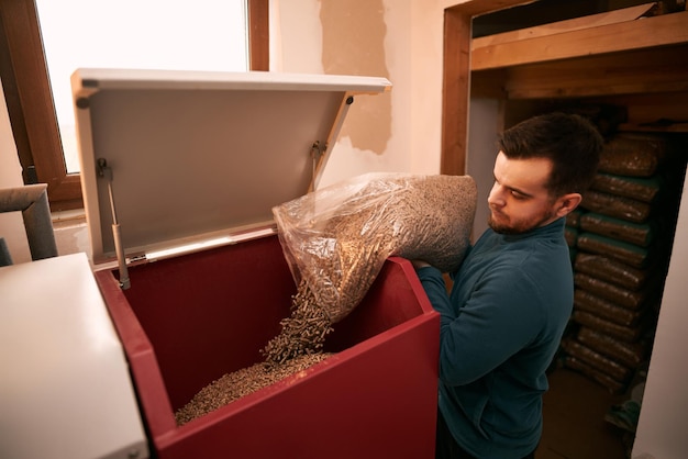 Nachhaltiges Zukunftskonzept Mann lädt Holzpellets in Heizofen mit Beutel Heizhaushalt im Winter