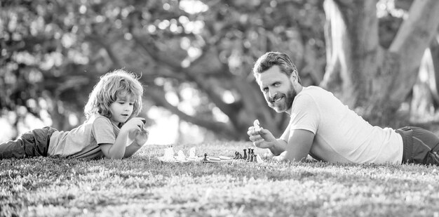 Nachhilfe Vater und Kind spielen Logikspiel Vater und Sohn spielen Schach und entspannen sich auf dem Rasen