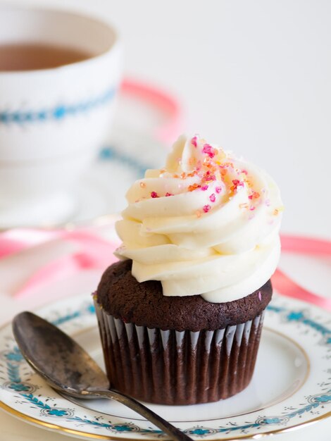 Nachmittagstee serviert mit einem weißen Cupcake.