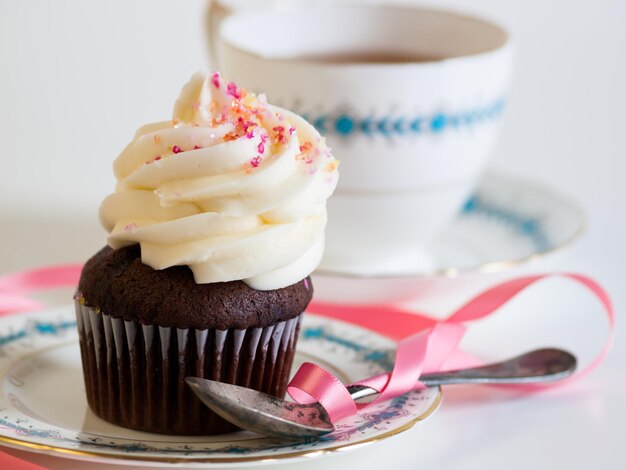 Nachmittagstee serviert mit einem weißen Cupcake.