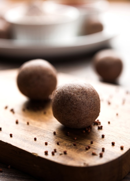 Nachni laddu o Ragi laddoo o bolas hechas con mijo, azúcar y ghee. Es un alimento saludable de la India. Servido en un bol o plato con crudo entero y en polvo. Enfoque selectivo