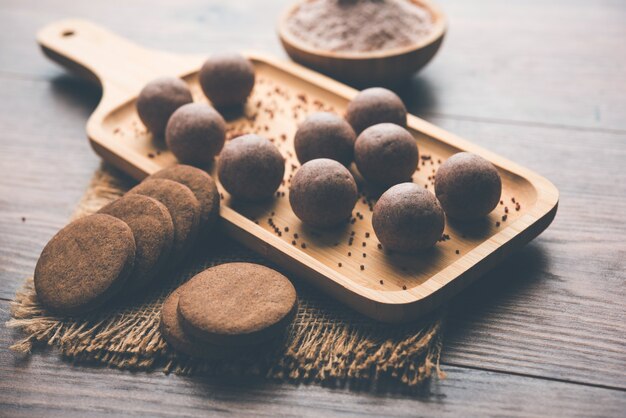 Nachni o Ragi laddu y bizcochos o galletitas elaboradas con mijo, azúcar y ghee. Es un alimento saludable de la India. Servido en un bol o plato con crudo entero y en polvo