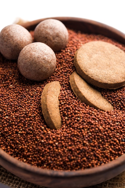 Nachni o Ragi laddu y bizcochos o galletitas elaboradas con mijo, azúcar y ghee. Es un alimento saludable de la India. Servido en un bol o plato con crudo entero y en polvo