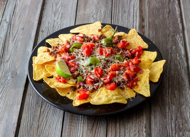 Foto nachos de chips de maíz con carne, queso, tomates y pimientos. comida mexicana. cocina nacional.