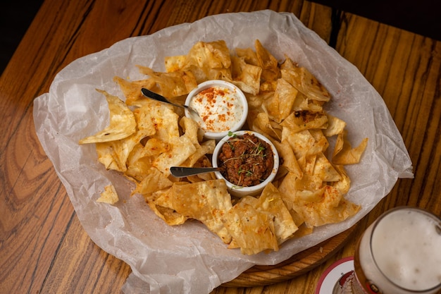 Nachos com molhos em pratos sobre uma mesa de madeira