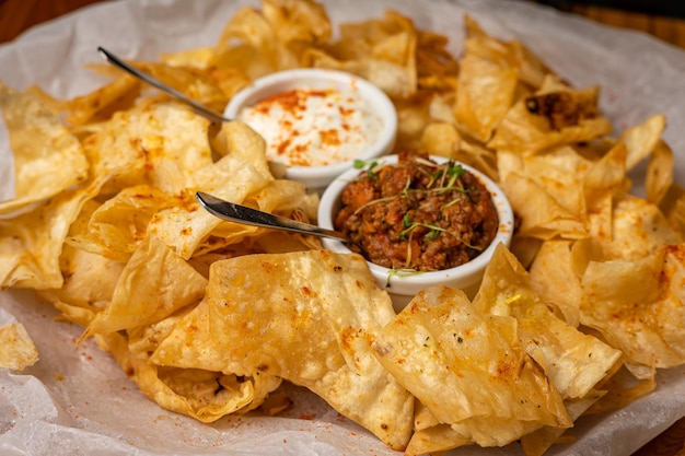 Nachos com molhos em pratos sobre uma mesa de madeira