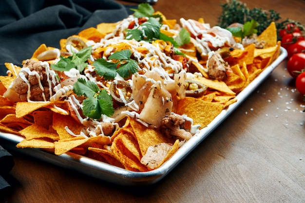 Nachos - Eine klassische mexikanische Vorspeise aus Maistortillachips. Nachos mit Saucen und Holopenya. Draufsicht. Nahansicht.