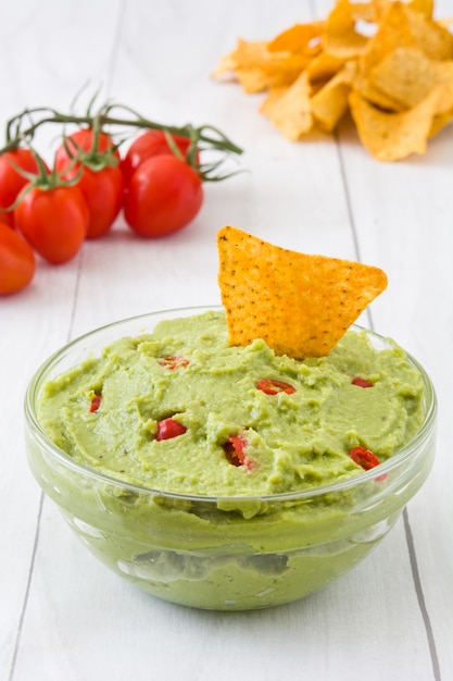 Nachos y guacamole en mesa de madera blanca