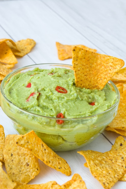 Nachos y guacamole en mesa de madera blanca