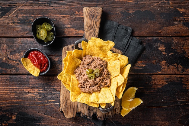 Nachos mexicanos al horno con chili con carne en una sartén Fondo de madera Vista superior