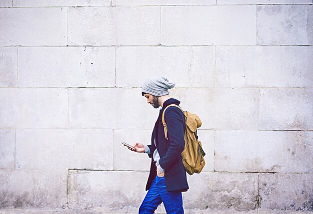 Nachrichten unterwegs Aufnahme eines jungen Mannes, der sein Handy benutzt, während er in der Stadt unterwegs ist