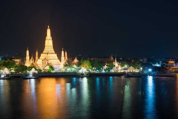 Nacht beleuchteter Tempel der Morgenröte oder Wat Arun und seine Reflexion im Fluss Chao Phraya nach Sonnenuntergang Bangkok Thailand