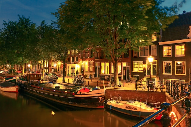 Nachtansicht der Stadt Amsterdam Kanal, Brücke und typische Häuser, Boote und Fahrräder, Holland, Niederlande.