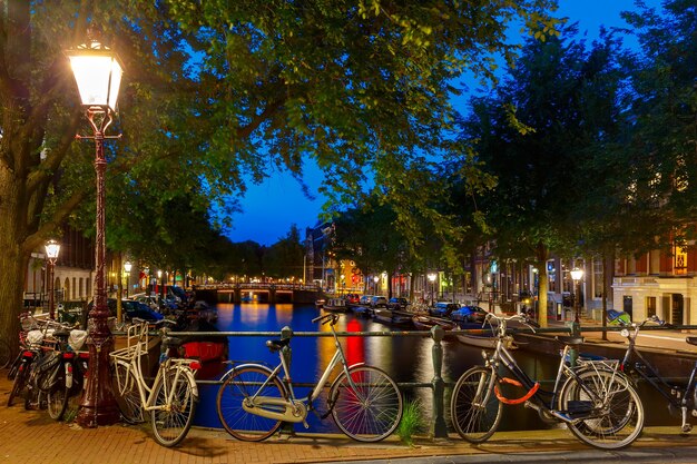 Nachtansicht der Stadt Amsterdam Kanal und Brücke, Boote und Fahrräder, Holland, Niederlande.