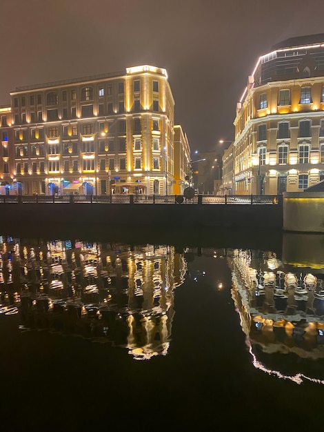 Nachtansicht der Stadt mit selektivem Fokus Neonlichter der Stadt spiegeln sich nachts auf dem Fluss wider