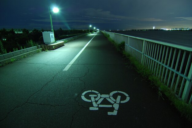 Nachtbild der Fahrradstraße, die weit weg auf der Bucht der Tokio-Bucht geht