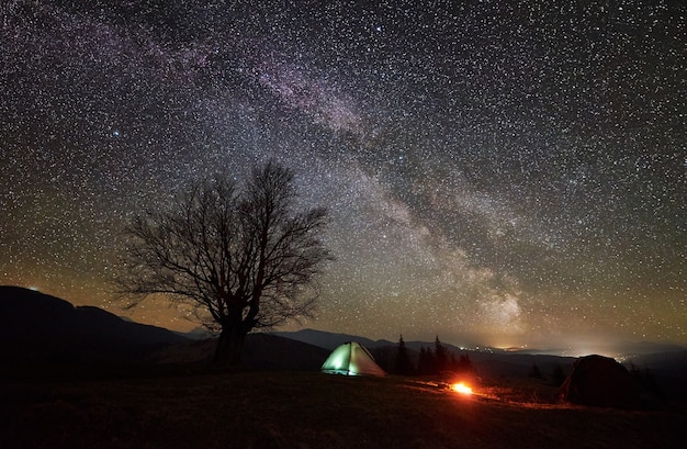 Nachtcamping im Gebirgstal unter Sternenhimmel