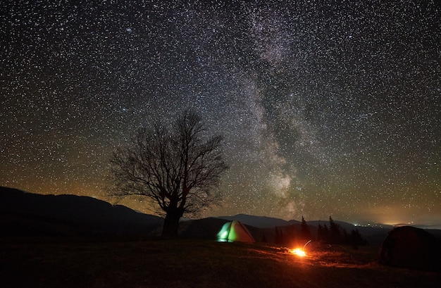 Nachtcamping im Gebirgstal unter Sternenhimmel