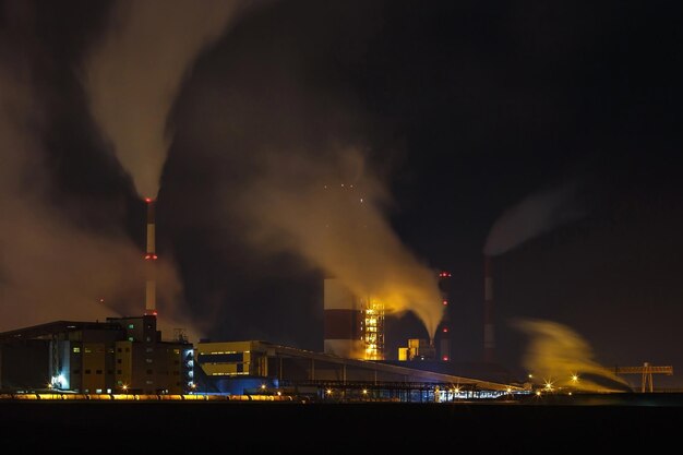 Nachtindustrielandschaft Umweltverschmutzung Abfall des Wärmekraftwerks Große Rohre der Unternehmensanlage der chemischen Industrie