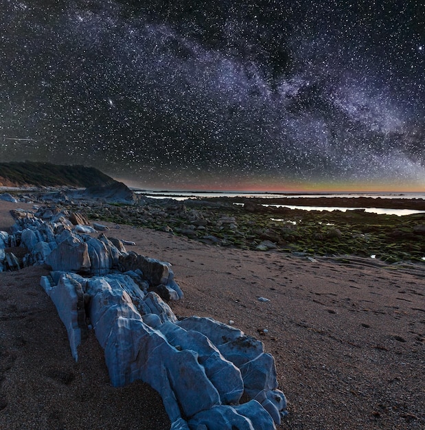 Nachtmeerblick vom Strand mit großen Steinen und sternenklarer Milchstraße im Himmel SaintJeandeLuz Frankreich Golf von Biskaya